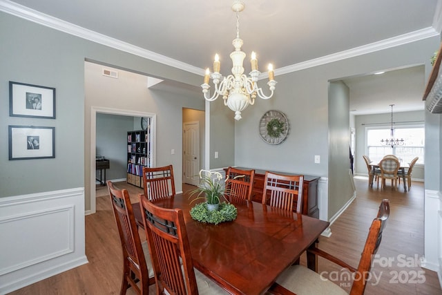 dining room with crown molding, a chandelier, and hardwood / wood-style floors