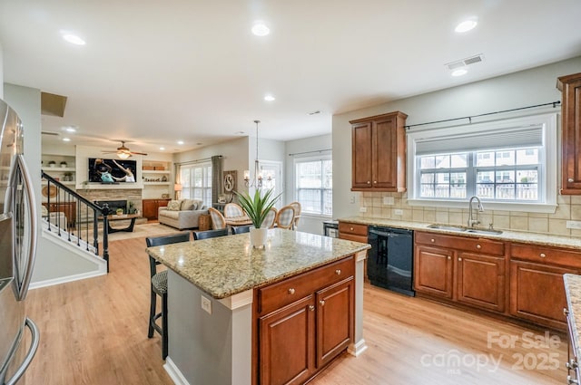 kitchen featuring sink, a center island, hanging light fixtures, a kitchen breakfast bar, and black dishwasher