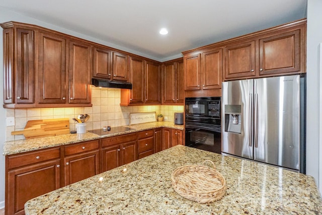 kitchen featuring backsplash, light stone counters, and black appliances