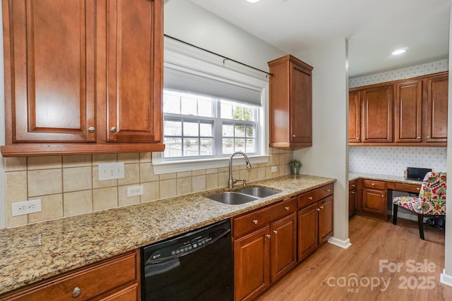 kitchen with built in desk, dishwasher, sink, light stone counters, and light hardwood / wood-style floors