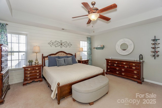 bedroom with a raised ceiling, light carpet, and multiple windows