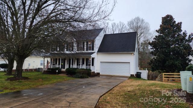 colonial home with a porch, a garage, and a front yard