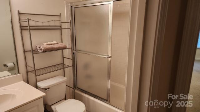 full bathroom featuring combined bath / shower with glass door, vanity, and toilet