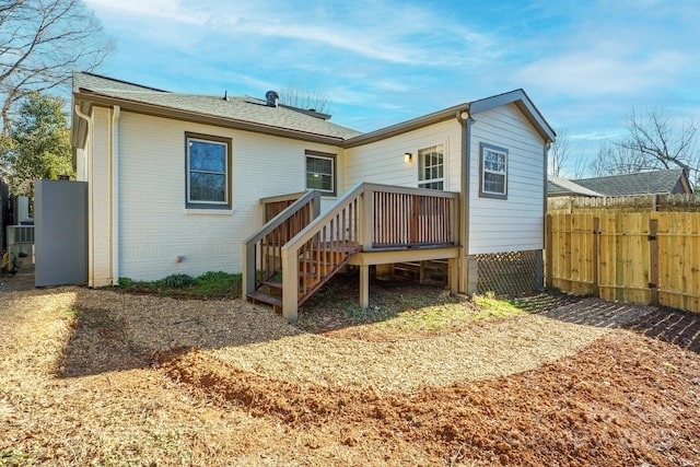 back of property featuring brick siding, a wooden deck, and fence