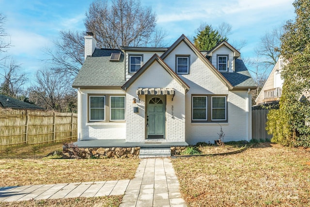 view of front of property with brick siding, a shingled roof, and fence