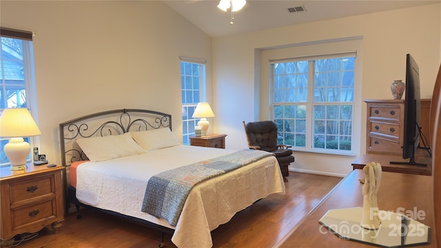 bedroom featuring hardwood / wood-style flooring, vaulted ceiling, and multiple windows