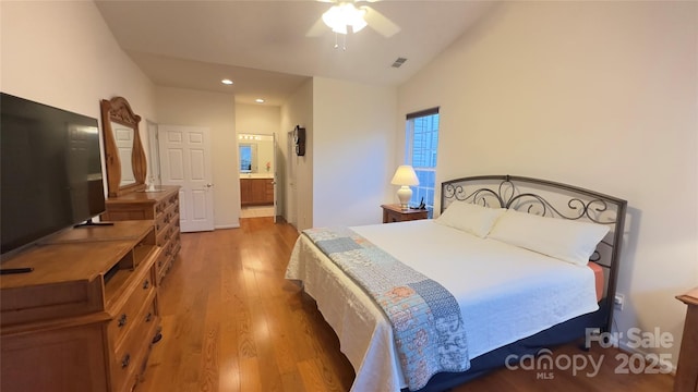 bedroom with ceiling fan, lofted ceiling, connected bathroom, and hardwood / wood-style floors