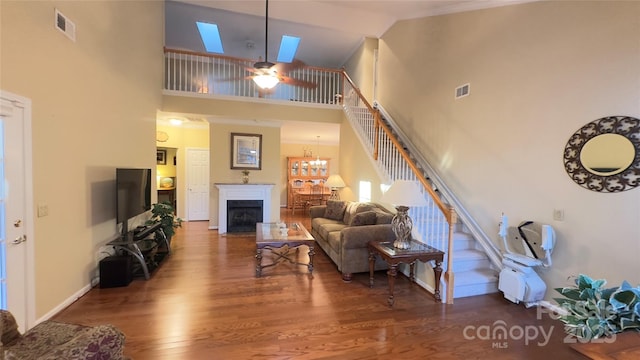 living room featuring ceiling fan with notable chandelier, wood-type flooring, and high vaulted ceiling