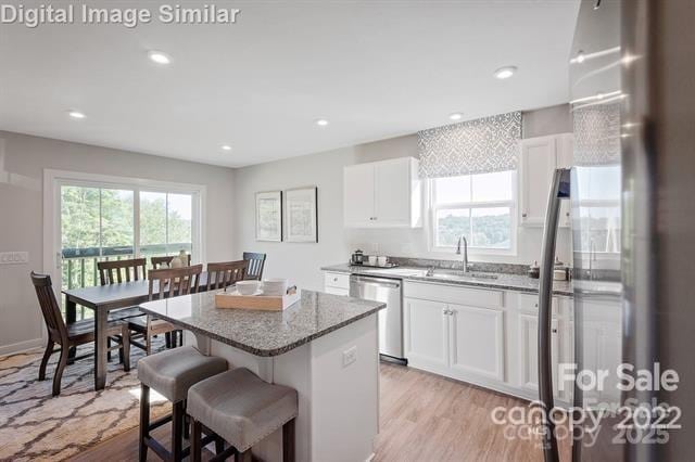 kitchen with white cabinetry, a breakfast bar area, appliances with stainless steel finishes, a kitchen island, and sink