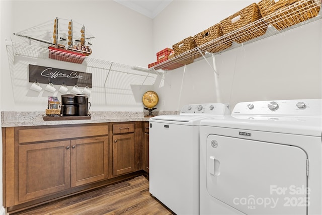 laundry area featuring hardwood / wood-style floors, cabinets, and washing machine and clothes dryer