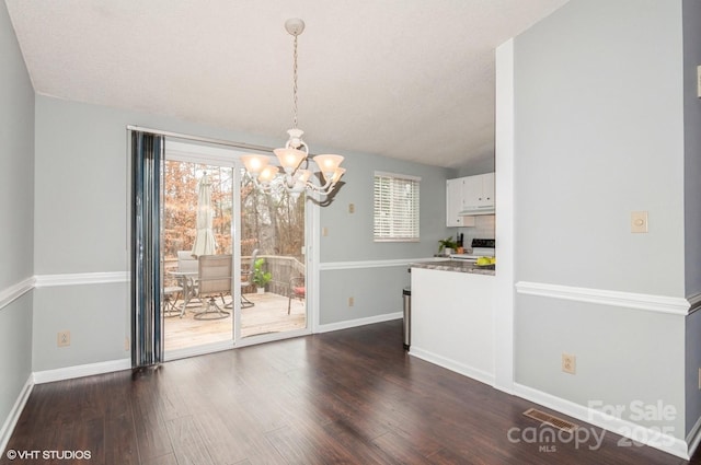 unfurnished dining area featuring dark hardwood / wood-style flooring, vaulted ceiling, and a notable chandelier