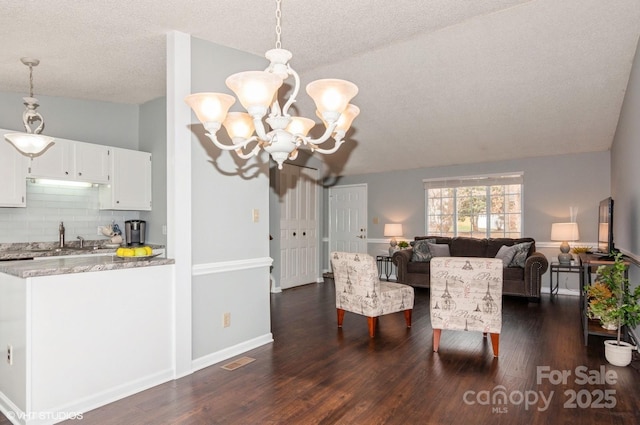 interior space featuring sink, a chandelier, vaulted ceiling, a textured ceiling, and dark hardwood / wood-style floors