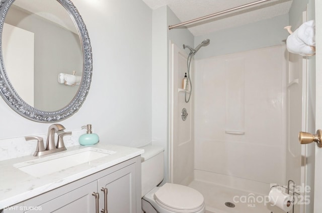 bathroom with a shower, vanity, a textured ceiling, and toilet