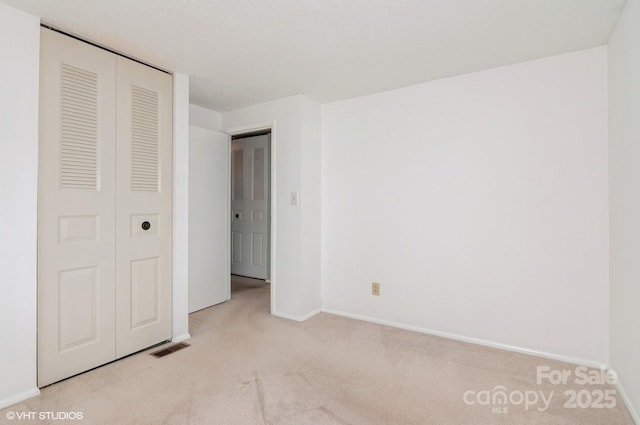 unfurnished bedroom with light carpet and a closet