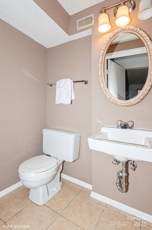 bathroom featuring tile patterned floors, toilet, and a textured ceiling