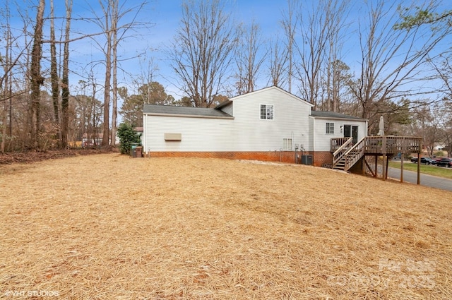 rear view of property with a wooden deck, a yard, and central air condition unit