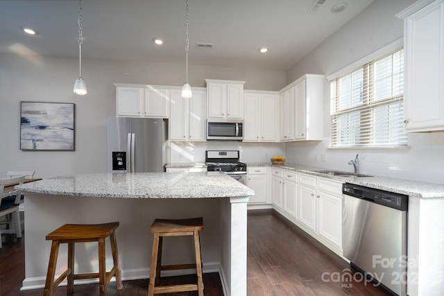 kitchen featuring sink, stainless steel appliances, white cabinetry, and decorative light fixtures