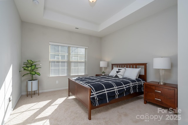 bedroom featuring light colored carpet and a tray ceiling