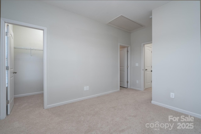 unfurnished bedroom featuring light colored carpet, a closet, and a walk in closet