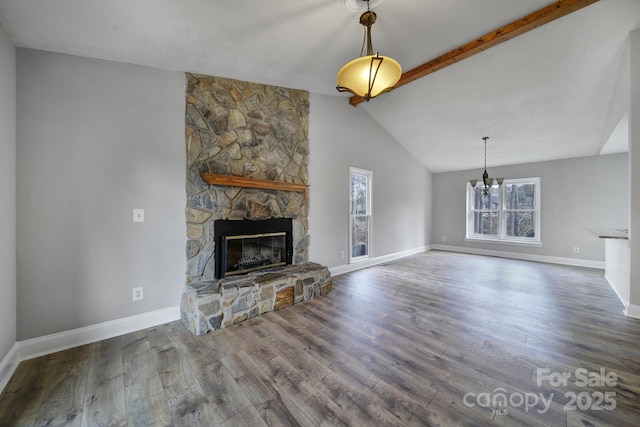 unfurnished living room with wood-type flooring, beam ceiling, a stone fireplace, and a notable chandelier