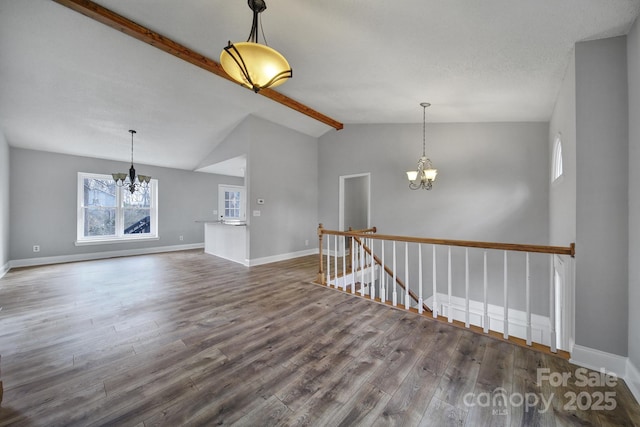 unfurnished living room with hardwood / wood-style flooring, vaulted ceiling with beams, and an inviting chandelier