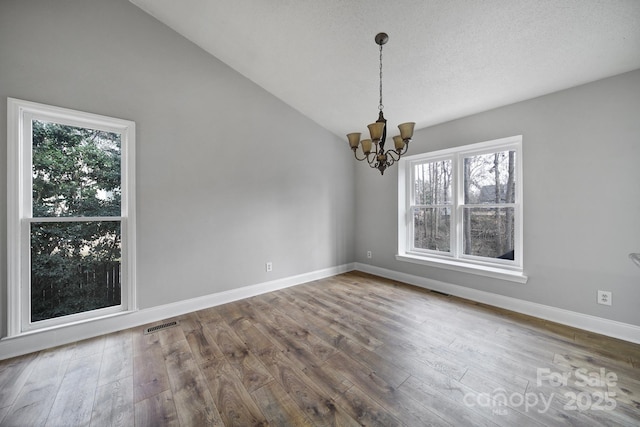 unfurnished room with lofted ceiling, hardwood / wood-style floors, and a notable chandelier