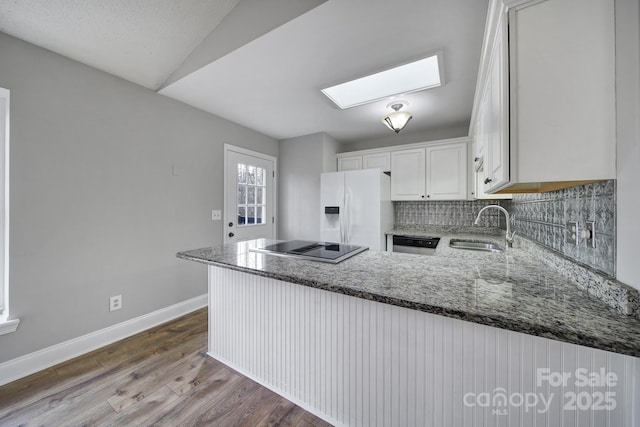 kitchen with white cabinetry, sink, white refrigerator with ice dispenser, and kitchen peninsula