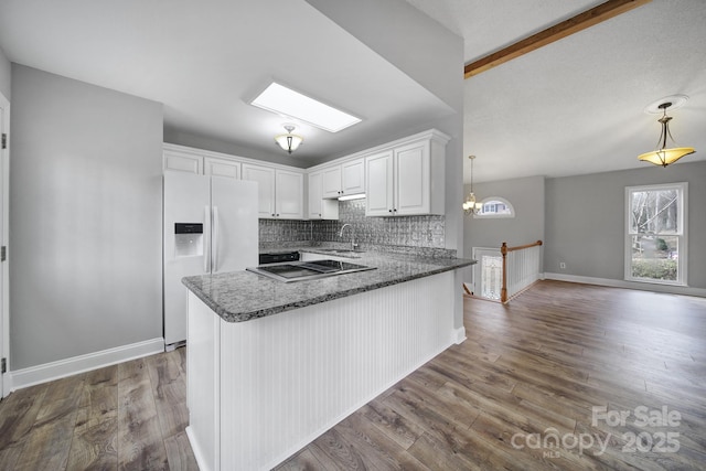 kitchen featuring white cabinetry, decorative light fixtures, white refrigerator with ice dispenser, and beamed ceiling