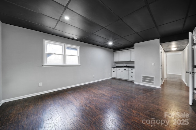 unfurnished living room featuring dark hardwood / wood-style floors and a paneled ceiling