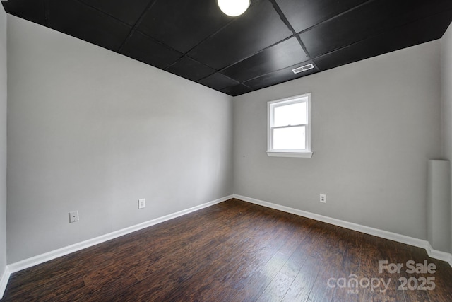 unfurnished room with dark hardwood / wood-style flooring and a paneled ceiling