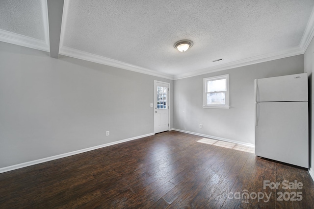 spare room featuring ornamental molding, dark wood-type flooring, and a textured ceiling