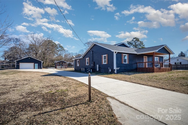 view of property exterior featuring a garage, a yard, an outdoor structure, and a porch