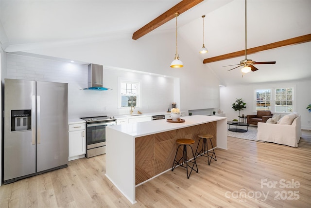 kitchen with appliances with stainless steel finishes, wall chimney exhaust hood, white cabinetry, a kitchen bar, and a kitchen island