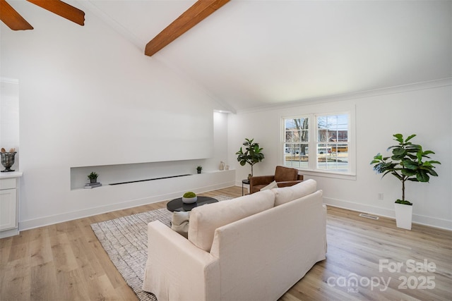 living room with light hardwood / wood-style flooring and vaulted ceiling with beams