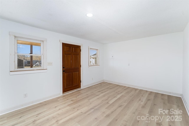 spare room with light wood-type flooring and a textured ceiling