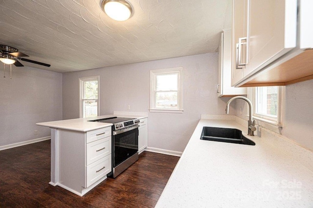 kitchen with electric stove, plenty of natural light, sink, and white cabinetry