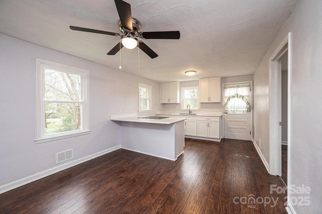 kitchen with white cabinetry, kitchen peninsula, a breakfast bar area, dark hardwood / wood-style floors, and sink