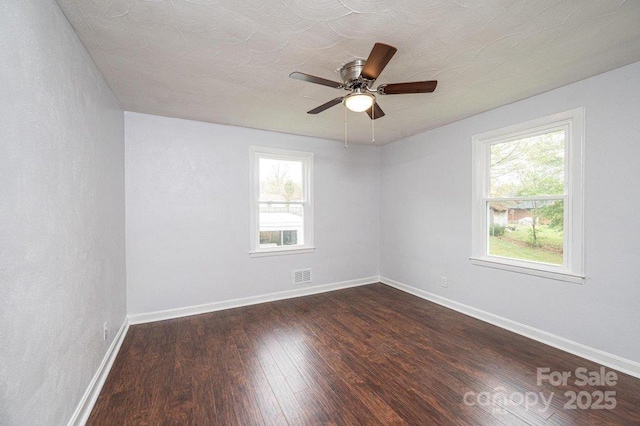 empty room featuring ceiling fan, dark hardwood / wood-style floors, and plenty of natural light