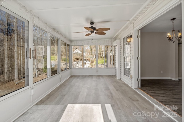 unfurnished sunroom featuring ceiling fan with notable chandelier