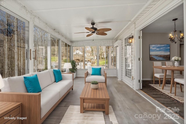 sunroom / solarium featuring ceiling fan with notable chandelier