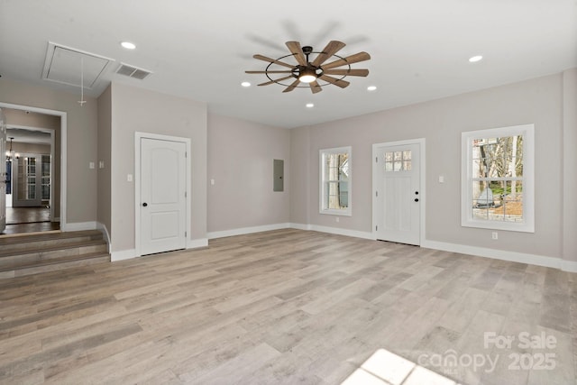 unfurnished living room with light wood finished floors, recessed lighting, visible vents, attic access, and electric panel