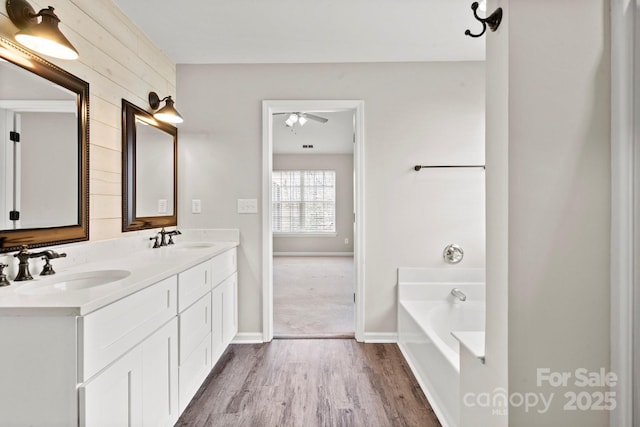 bathroom featuring wood finished floors, a garden tub, a sink, and double vanity