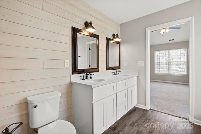 bathroom featuring double vanity, wood finished floors, a sink, and toilet