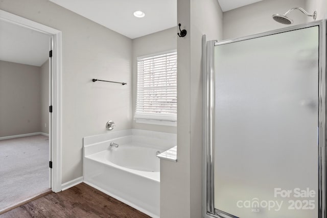 full bath featuring wood finished floors, a shower stall, a bath, and baseboards