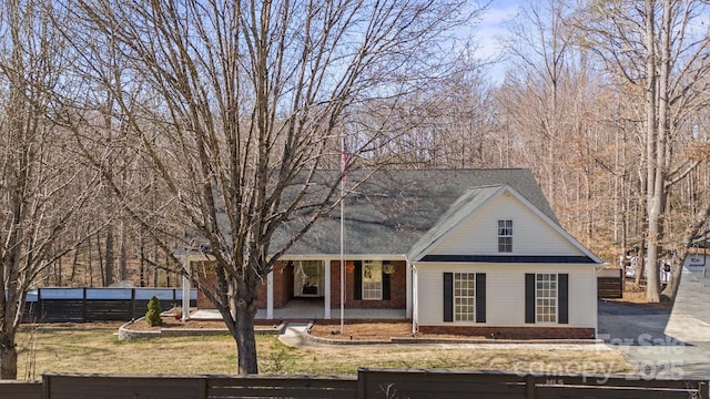 traditional home featuring a fenced front yard, a shingled roof, and brick siding