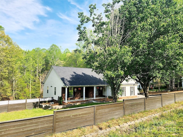 view of front of home featuring a porch, roof with shingles, and a fenced front yard