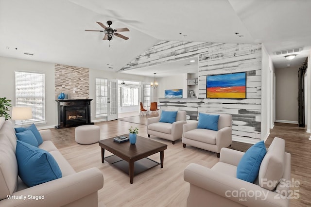 living area featuring light wood finished floors, visible vents, ceiling fan with notable chandelier, and baseboards