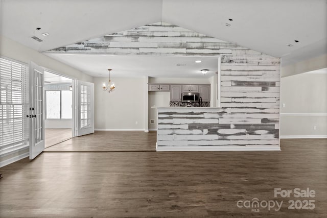 unfurnished living room with baseboards, a chandelier, and vaulted ceiling