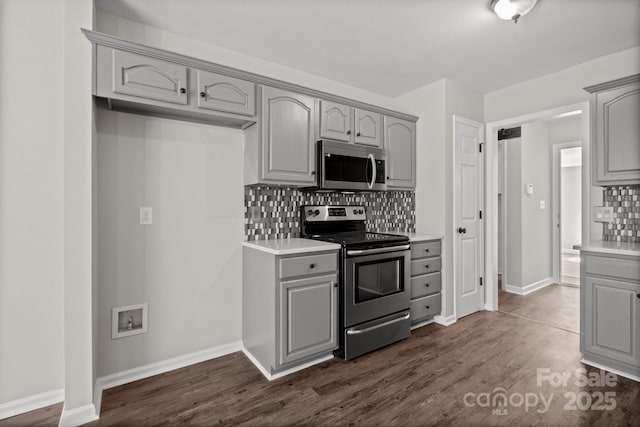 kitchen featuring dark wood-style floors, gray cabinetry, backsplash, and stainless steel appliances