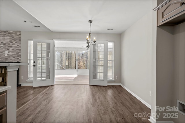 unfurnished dining area featuring a chandelier, dark wood-type flooring, visible vents, and baseboards